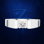 A silver-toned men's ring with a large round brilliant-cut diamond center stone, presented against a textured dark blue background with a stylized blue 'Z' logo.
