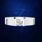 A silver-toned ring with a single round-cut clear gemstone in a prong setting, centered against a dark blue textured background with a large stylized blue number 7 behind it.