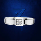 A silver-toned men's band ring with a square bezel holding a round brilliant-cut diamond, presented against a textured dark blue background with a stylized blue 'Z' logo.