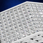 A close-up of a white geometric display tray filled with many clear faceted gemstones arranged in rows against a dark blue background.