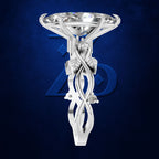 A white gold or platinum engagement ring featuring a large round brilliant-cut diamond and an intricate sculpted shank with swirling details and a small accent stone, set against a dark blue textured background with a subtle blue logo.