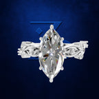 A silver-toned ring featuring a large marquise-cut clear gemstone in a prong setting, with ornate woven side bands, shown against a dark blue textured background.