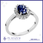 A silver-plated halo ring featuring a round deep blue sapphire center stone and surrounded by small clear accent stones, shown on a white background with the Platisem brand logo at the bottom.