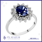 A platinum ring featuring a large oval-cut deep blue sapphire center stone, surrounded by a halo of round brilliant-cut clear diamonds, set on a polished silver-colored band. The brand logo 'PLATIZEM' is visible at the bottom of the image.