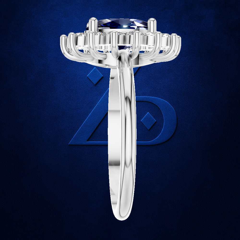 A silver-toned solitaire ring featuring a round brilliant-cut blue gemstone in a prong setting, shown against a textured dark blue background with a subtle logo.