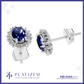 A pair of silver stud earrings with oval-cut deep blue gemstones and small clear accent stones, shown on a white background with the PLATIZEM brand logo at the bottom.