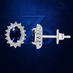 A pair of oval-cut blue sapphire stud earrings with diamond halo settings in silver-tone metal, shown from both front and side/back angles against a dark blue textured background with a subtle logo.