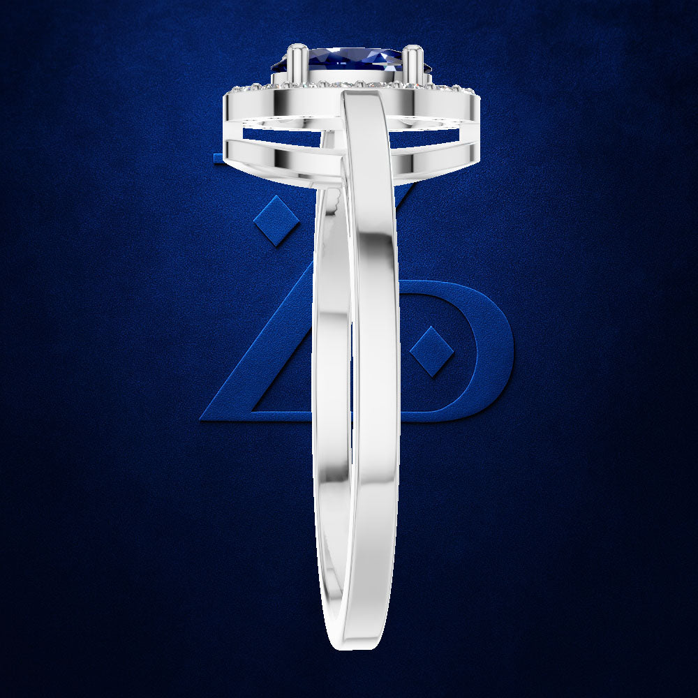 A silver-toned diamond ring with a round-cut blue sapphire center stone, shown in a side profile view against a textured dark blue background.