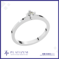 A silver solitaire ring with a round brilliant-cut diamond set in a four-prong setting, displayed on a white background with a blue border and the Platizem brand logo at the bottom.