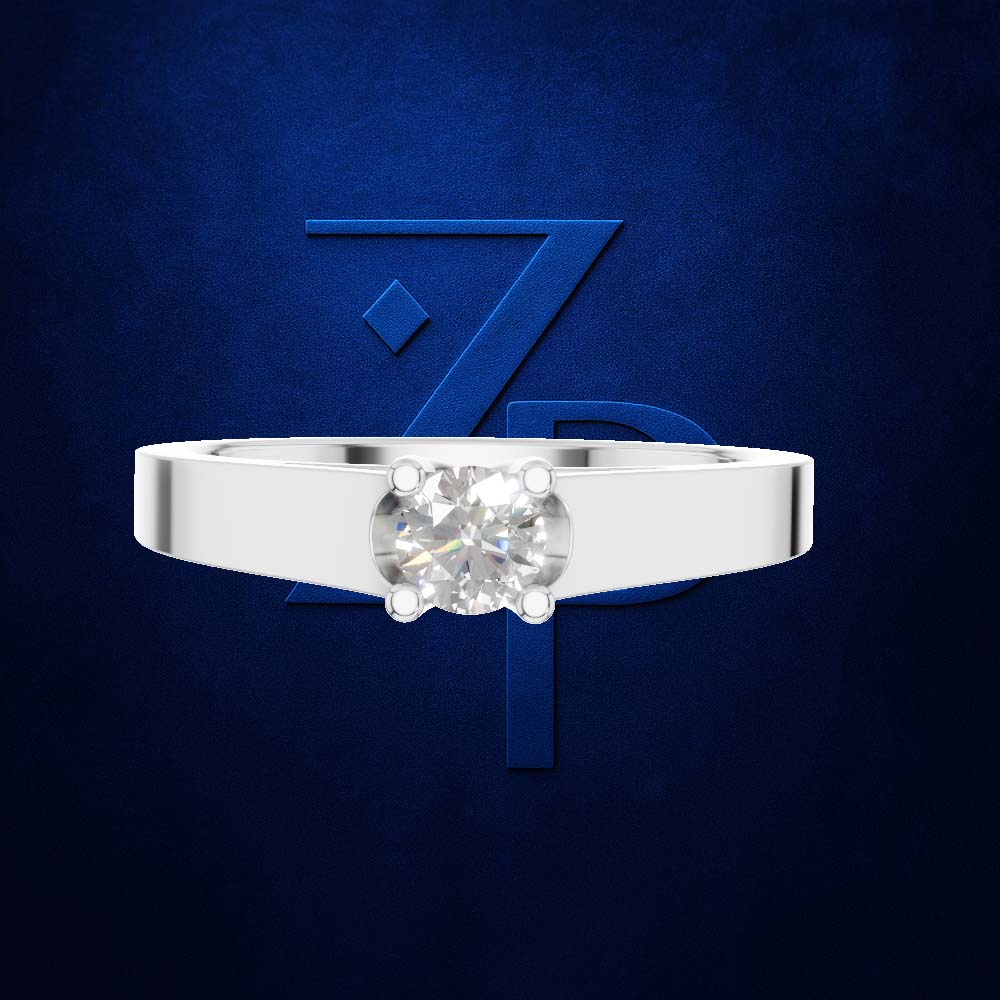 A silver solitaire ring with a round brilliant-cut diamond set in a four-prong setting, presented against a textured dark blue background with a stylized blue 'Z' logo.