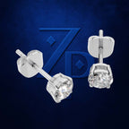 A pair of silver stud earrings with round clear gemstones, shown from both front and back views against a textured dark blue background with a stylized 'ZPD' logo.
