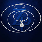 A silver-toned chain necklace with a round-cut clear gemstone pendant, arranged in concentric loops over a dark blue textured background with a large stylized blue ZP logo.