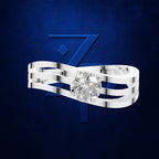 A silver-toned triple-band ring with a round-cut clear gemstone, presented against a textured dark blue background with a stylized blue 'Z' logo.