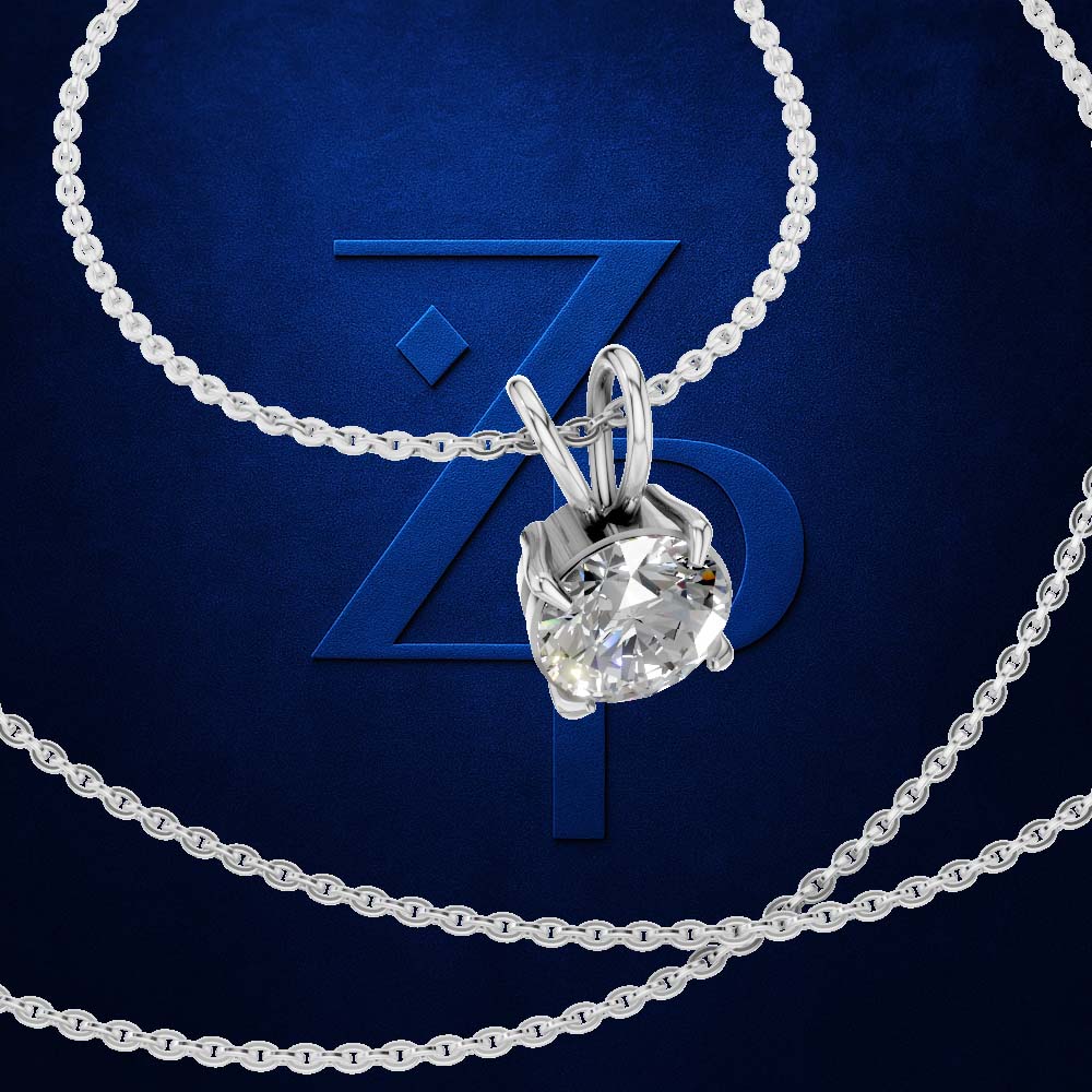A silver-toned necklace with a bezel-set clear gemstone pendant, arranged on a dark blue background with a large stylized 'Z' logo behind it.