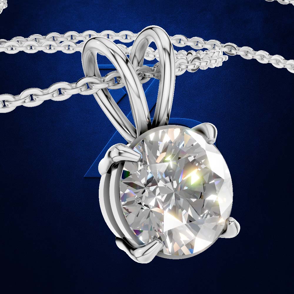 A silver-toned solitaire pendant necklace featuring a large, round brilliant-cut clear gemstone in a prong setting, suspended from a matching chain against a dark blue textured background.