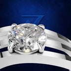 A close-up studio render of a solitaire diamond ring with a round brilliant-cut center stone in a silver-toned setting, mounted on a curved silver band against a deep blue background with a subtle geometric logo.