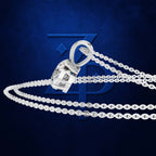 A silver-toned pendant necklace with a faceted clear gemstone in a bezel setting, shown on a dark blue textured background with a faint blue logo behind it.