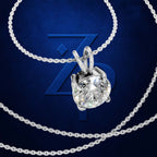A silver-tone necklace with a round brilliant-cut clear gemstone pendant, displayed on a dark blue background with a large stylized 'Z' logo and additional chain loops.