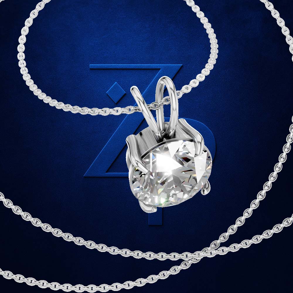 A silver-toned necklace with a bezel-set round clear gemstone pendant, arranged on a dark blue background with a large stylized 'Z' logo behind it.