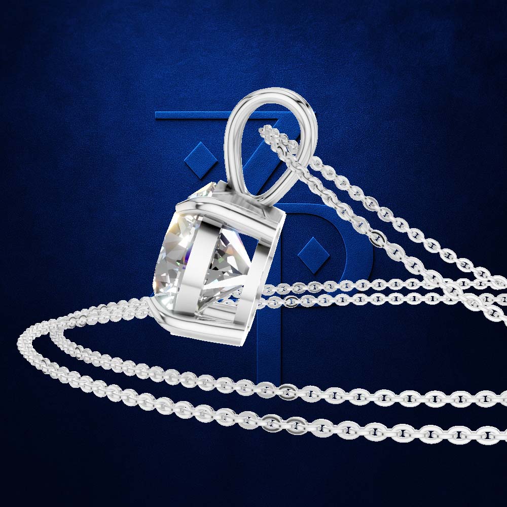 A silver pendant necklace with a bezel-set clear gemstone, shown on a dark blue textured background with a stylized blue 'T' backdrop and chain draped across the frame.