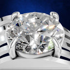 A close-up studio shot of a solitaire diamond ring with a large oval-cut clear gemstone in a polished silver-toned setting, shown against a dark blue background with white curved decorative elements.