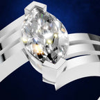 A close-up studio shot of a silver ring featuring a large, marquise-cut clear gemstone in a prong setting, mounted on a multi-band silver band. The background is a deep textured blue.