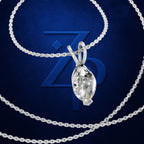 A silver-toned necklace with a marquise-cut clear gemstone pendant, displayed on a textured dark blue background with a large stylized 'ZP' logo behind it.