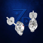 A pair of silver-toned teardrop stud earrings with clear faceted gemstones, shown from front and side angles against a dark blue textured background with a subtle stylized 'ZP' logo.