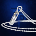 A silver-toned pendant necklace with a geometric, faceted triangular pendant and matching chain, displayed against a dark blue textured background with a large stylized 'TP' logo.