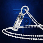 A silver-toned pendant necklace with a faceted geometric drop pendant and a link chain, displayed against a dark blue textured background with a faint stylized logo.