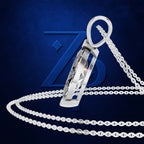A silver-toned pendant necklace with a faceted rectangular drop and a matching chain, displayed on a dark blue textured background with a large stylized Z logo.
