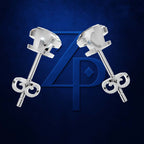 A pair of polished silver stud earrings with round faceted clear gemstones and butterfly backings, displayed against a dark blue textured background with a large blue monogram logo.