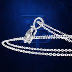 A silver-toned pendant necklace with a large clear marquise-cut gemstone in a bezel setting, shown on a dark blue textured background with a faint blue logo behind it.
