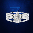 A silver-toned multi-band ring featuring a large pear-cut clear gemstone, presented against a textured dark blue background with a stylized blue 'Z' logo.