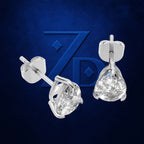 A pair of silver stud earrings with clear teardrop-shaped gemstones, shown from different angles against a dark blue textured background with a stylized 'ZD' logo.