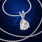 A silver-tone pendant necklace with a pear-cut clear gemstone in a prong setting, shown on a dark blue textured background with a large stylized 'Z' logo behind it.