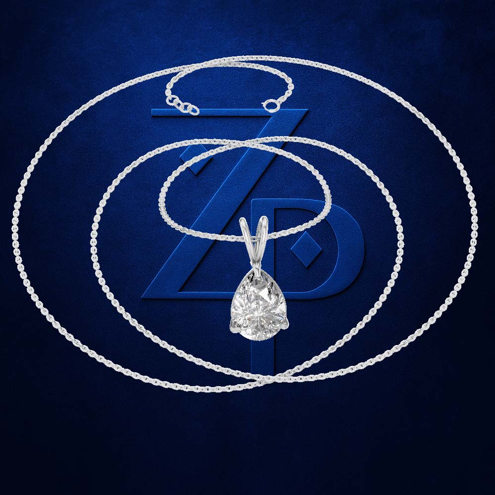 A silver-toned necklace with a teardrop-shaped clear gemstone pendant, displayed against a dark blue textured background with a large stylized blue ZD logo.