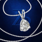 A silver-toned pendant necklace with a large, round brilliant-cut clear gemstone, displayed on a textured dark blue background with a large blue 'Z' logo behind it.