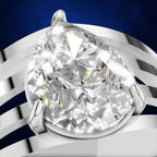 A pear-cut diamond ring set in a polished silver-toned band, shown in a close-up studio shot against a dark blue and white striped background.
