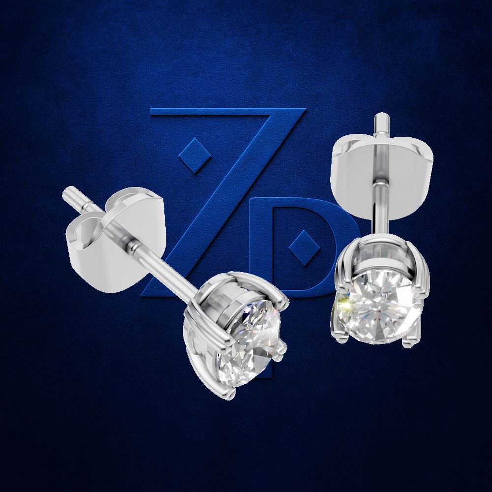 A pair of silver stud earrings with clear round-cut gemstones, shown from both front and side/back views against a textured dark blue background with a stylized 'ZPD' logo.