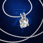 A silver-tone solitaire necklace with a round-cut clear gemstone pendant, displayed on a dark blue background with a large stylized 'ZP' logo behind it.