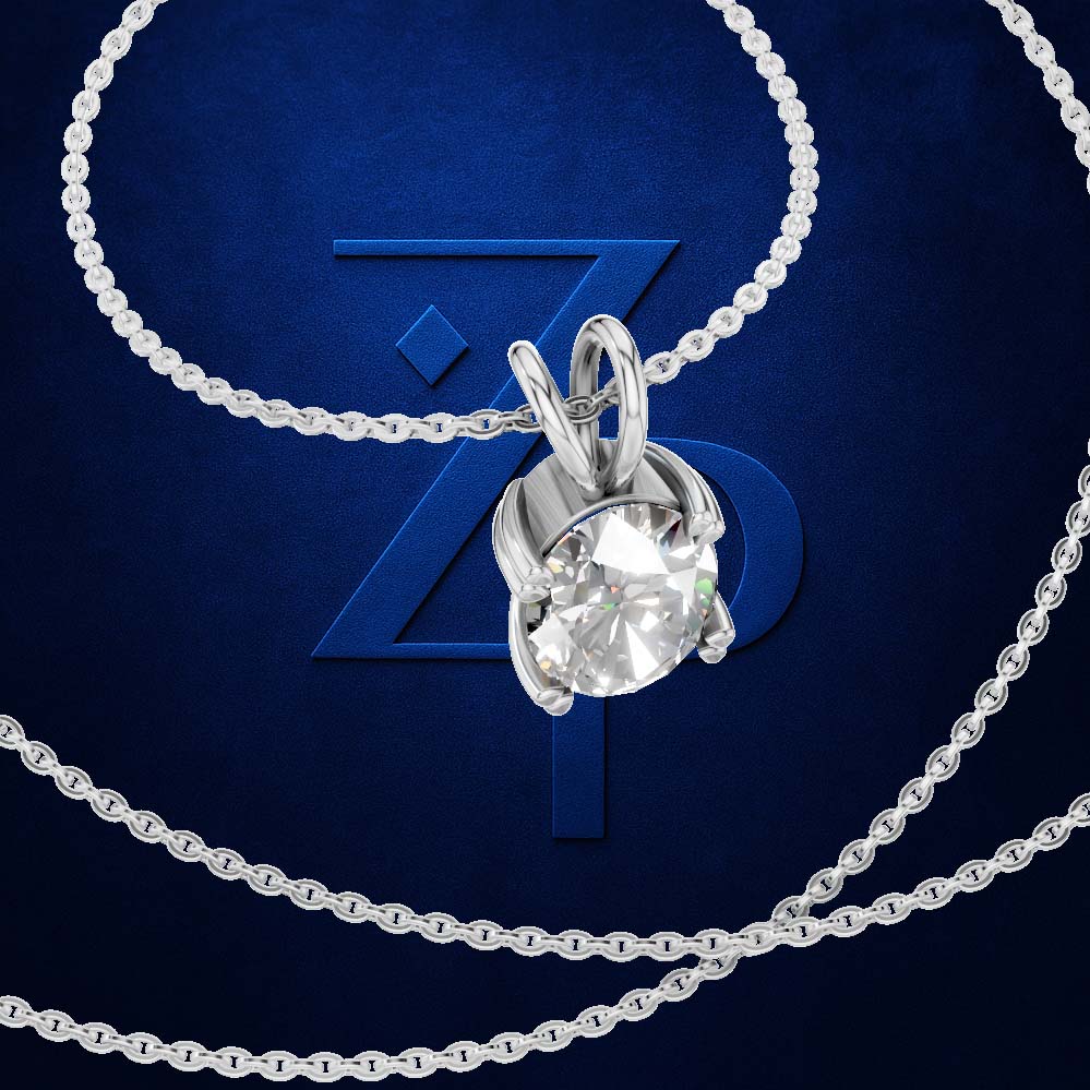 A silver-tone solitaire necklace with a round-cut clear gemstone pendant, displayed on a dark blue background with a large stylized 'ZP' logo behind it.