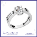 A silver-toned solitaire engagement ring with a round brilliant-cut diamond set in a high-profile crown, presented on a white background with a blue border and the Platizem brand logo at the bottom.