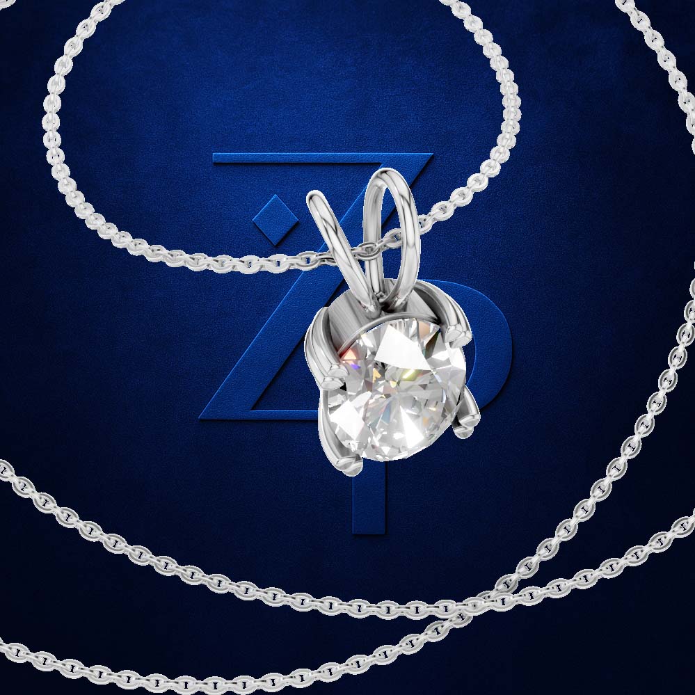 A silver-tone solitaire necklace with a round brilliant-cut clear gemstone pendant, displayed on a dark blue textured background with a stylized blue 'Z' logo.
