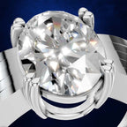 A close-up studio rendering of a silver-toned ring with a large oval clear gemstone in a prong setting, shown against a dark blue background.