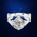 A silver-toned ring featuring a large, brilliant-cut clear gemstone in a shield-like setting with curved side bands, centered against a textured dark blue background.