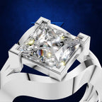 A radiant cut diamond ring in a silver-toned setting with a white ribbon-like band, shown against a dark blue textured background.