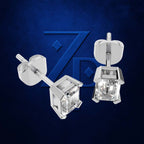 A pair of silver stud earrings with clear faceted cubic zirconia stones, shown from both front and side angles against a textured dark blue background with a subtle brand logo.
