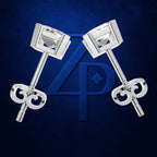 A pair of silver-toned stud earrings with square-cut clear stones and decorative curved backings, displayed on a dark blue textured background with a large blue monogram logo behind them.