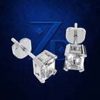 A pair of silver-toned stud earrings with square-cut clear gemstones, shown from front and side angles against a textured dark blue background with a subtle stylized logo.